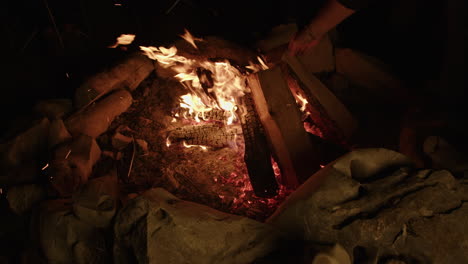 Knisterndes-Lagerfeuer-In-Zeitlupe,-Das-Mit-Abfliegendem-Brennholz-Und-Glut-Gepflegt-Wird