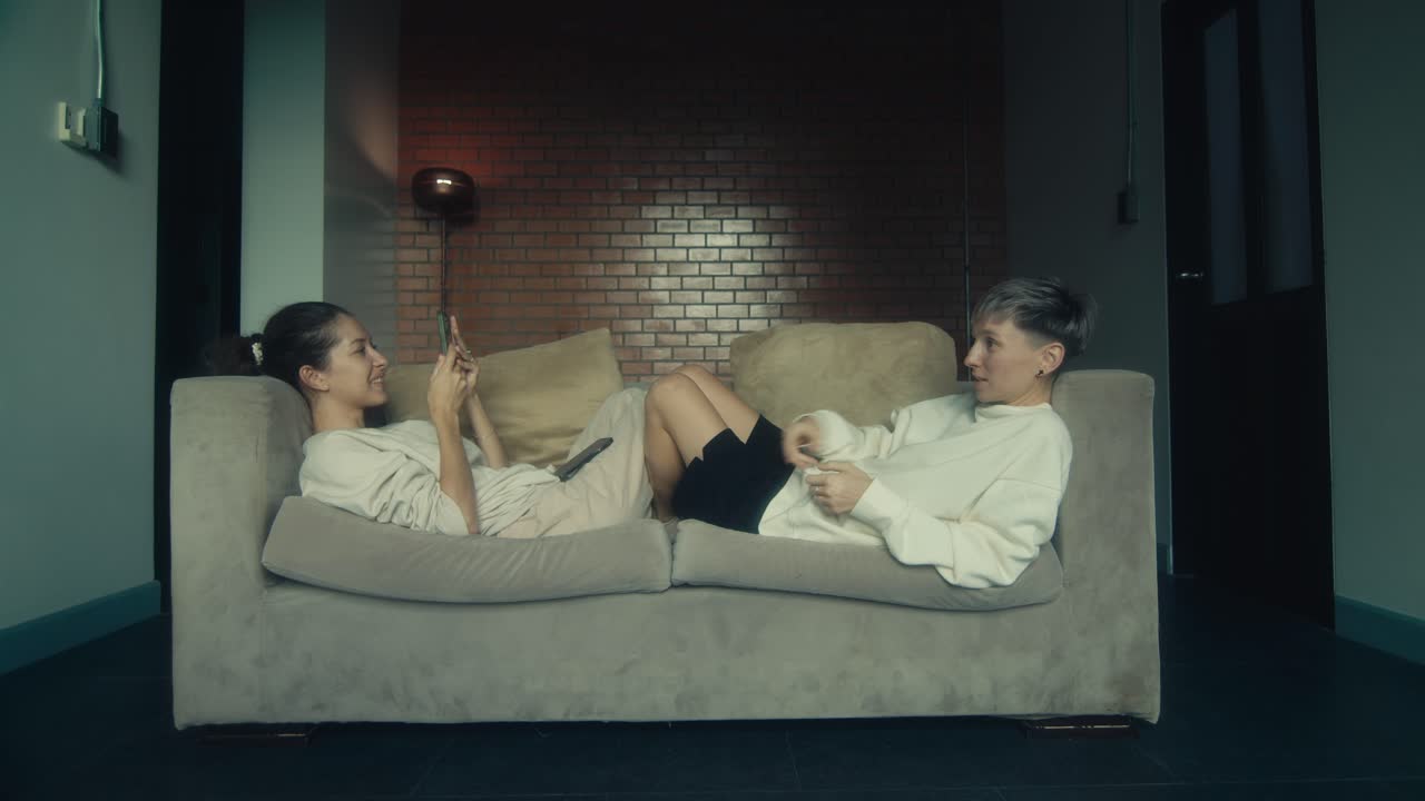 Two Women Relaxing on Sofa with Smartphones