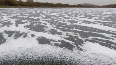 cold blowing snow accumulating along cracks in ice as the water freezes