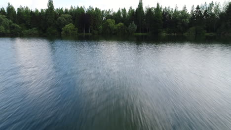 Schneller-Drohnenflug-über-Einem-See-In-Frankreich-Mit-Bäumen-Im-Hintergrund.