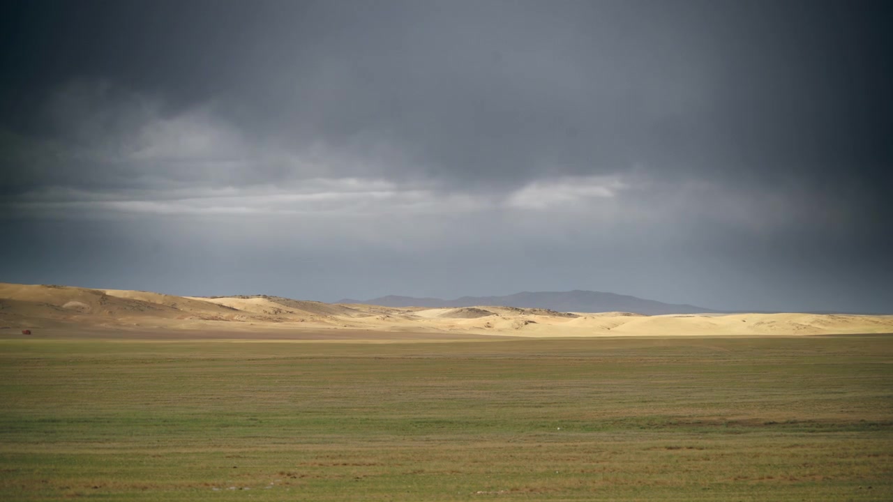 Myrskyisät pilvet laajan Mongolian aron ja hiekkadyynien yllä