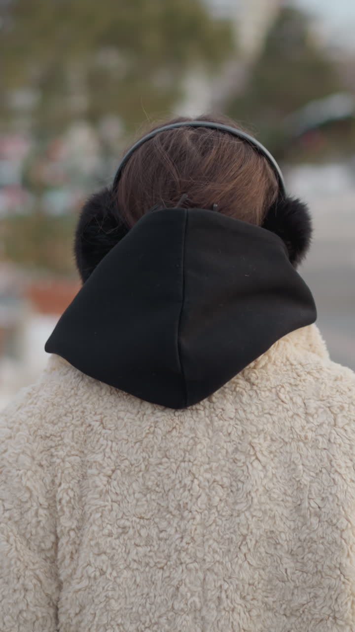 셰르파 코트와 검은색 귀마개를 착용하고 외부에서 생각에 잠긴 듯한 표정으로 거리를 바라보는 백인 십 대 소녀, 버스나 누군가를 기다리는 듯한 차분하고 부드러운 영화 같은 분위기, 구경하는 사람은 없음