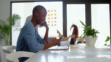 Side-view-of-young-black-businesswoman-sitting-at-table-and-working-on-smartphone-4k