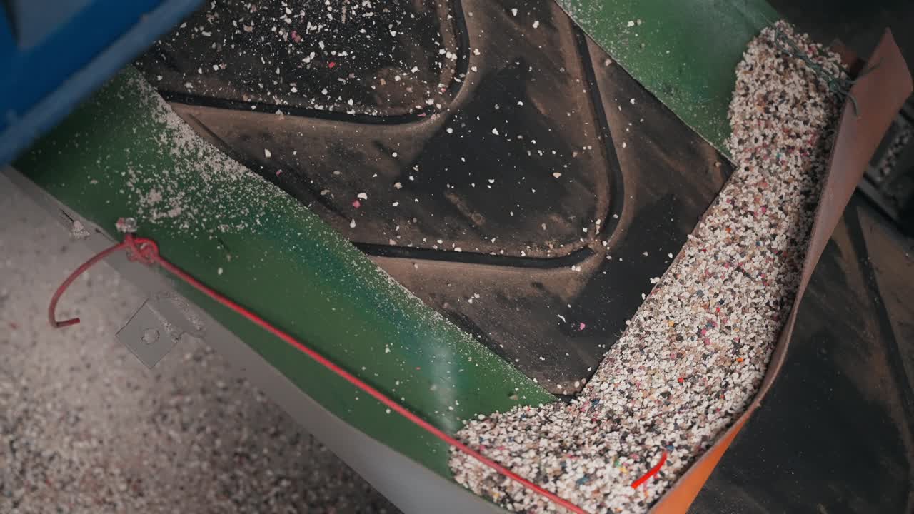 Processed rubber granulate flowing along conveyor inside recycling factory