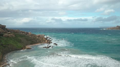 AERIAL:-Mediterranean-Sea-Rolls-Waves-to-Ghajn-Tuffieha-Bay-on-a-Rocky-Beach