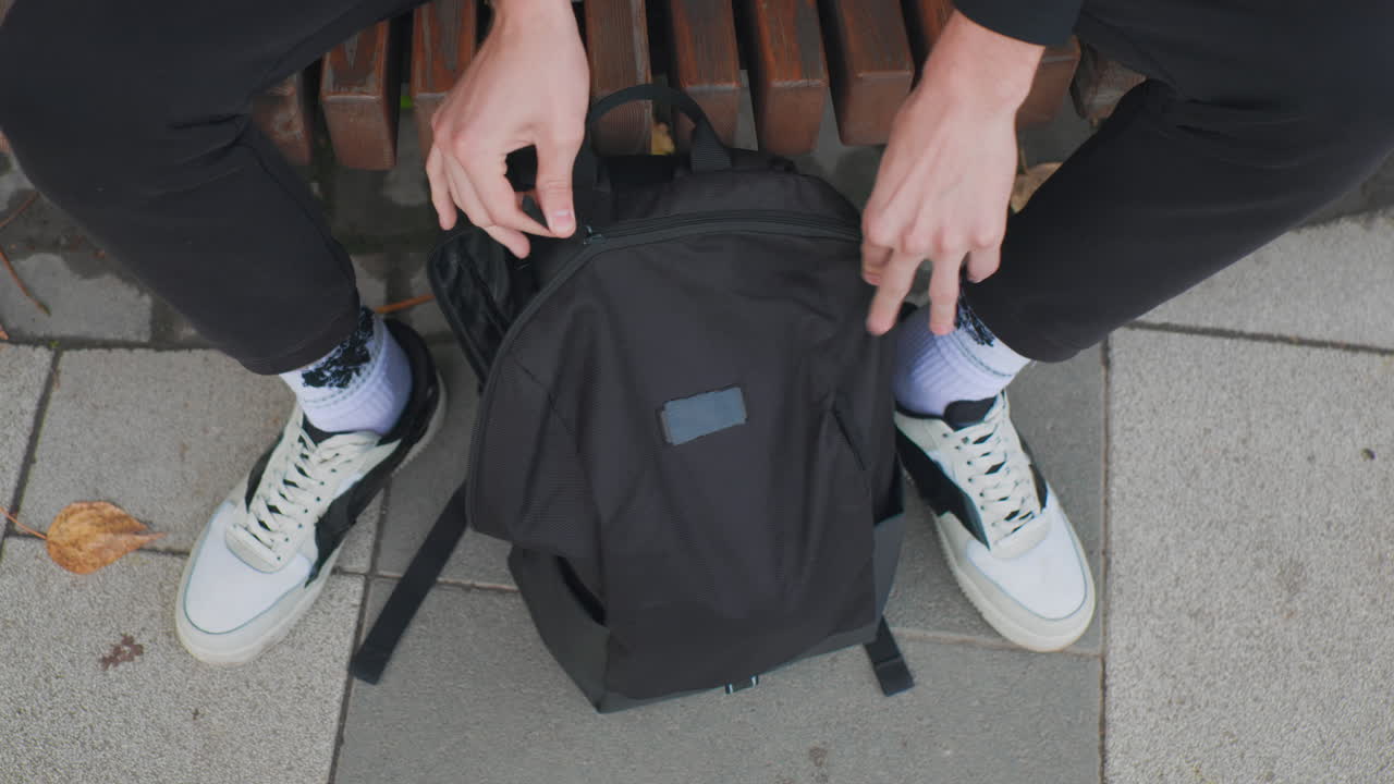 Cyclist organizing gear before starting journey, Male rider securing helmet in backpack prior to departure, Urban male cyclist double checking helmet straps and zippers before leaving