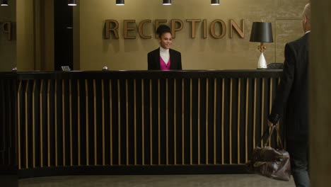 man receiving his room key at the hotel reception desk