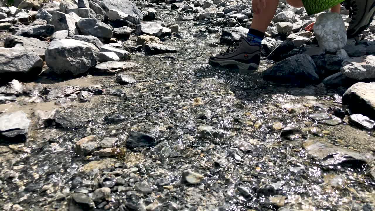 폭포에서 오는 산 강에서 걷고 돌을 가지고 노는 귀여운 소년