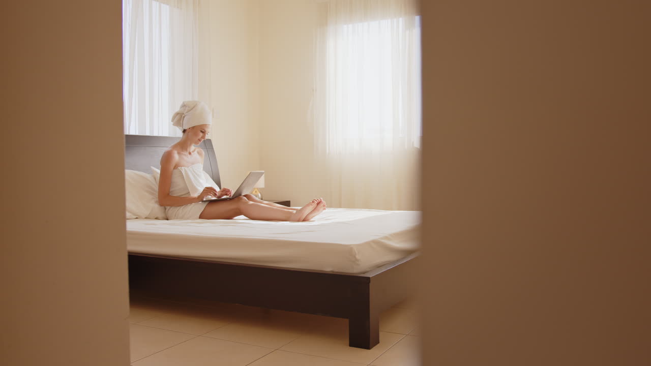 침대에 노트북으로 일하는 여자