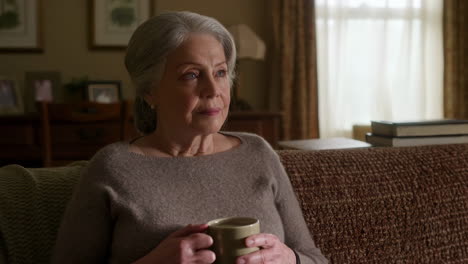 elderly woman relaxing on sofa with a mug