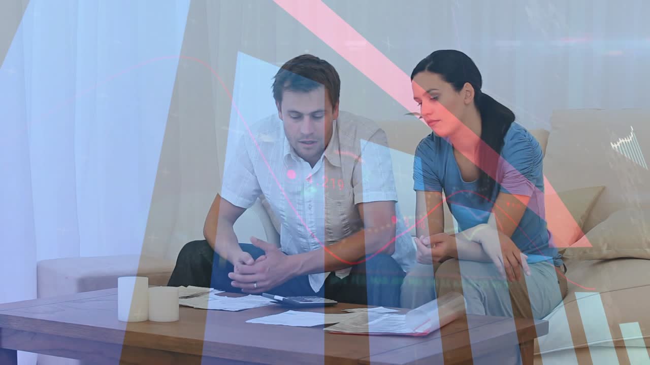 Pair sitting on couch reviewing bills, tapping tablet activating financial charts, sorting finances