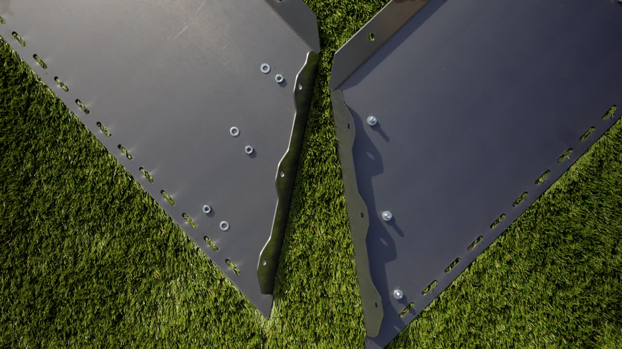 Two powder coated metal panels with bolts and washers laid on grass, ready for outdoor assembly