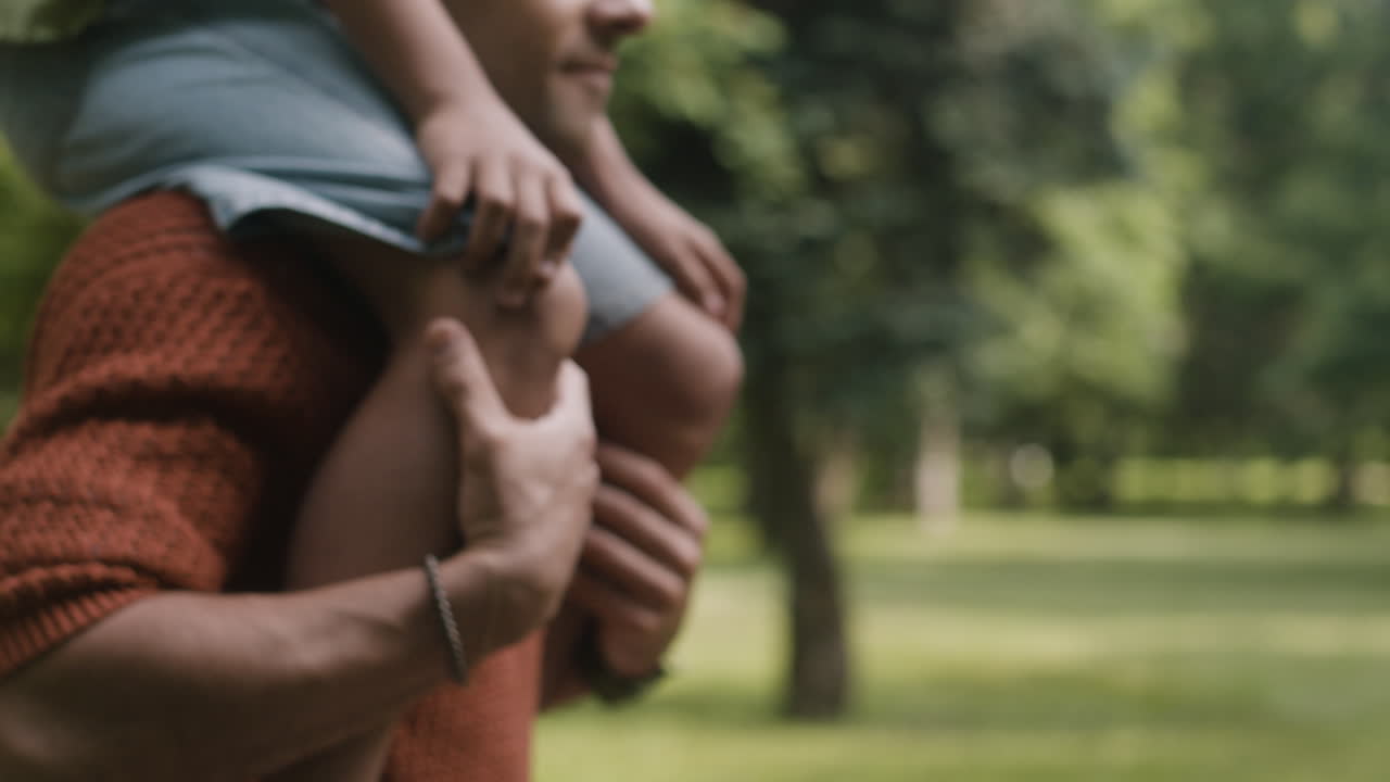Father carrying daughter on shoulders in park