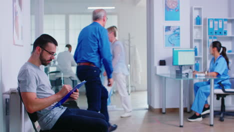 Man-filling-paperwork-in-hospital-waiting-area