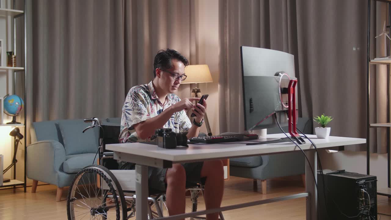hombre en silla de ruedas usando teléfono inteligente en la oficina de casa por la noche