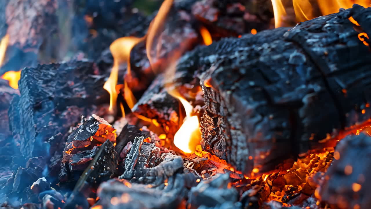 A pile of burnt wood with a lot of black and orange colors. The fire has left a lot of ash and charred wood, which gives the scene a smoky and charred appearance. Scene is somewhat eerie