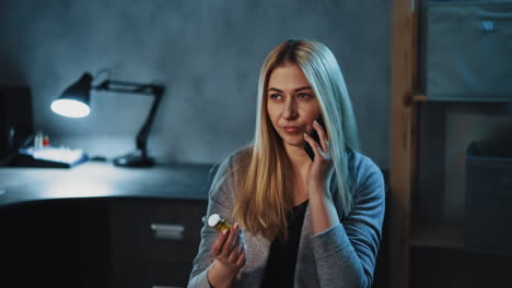 doubting woman calls on phone holding pill bottle in room