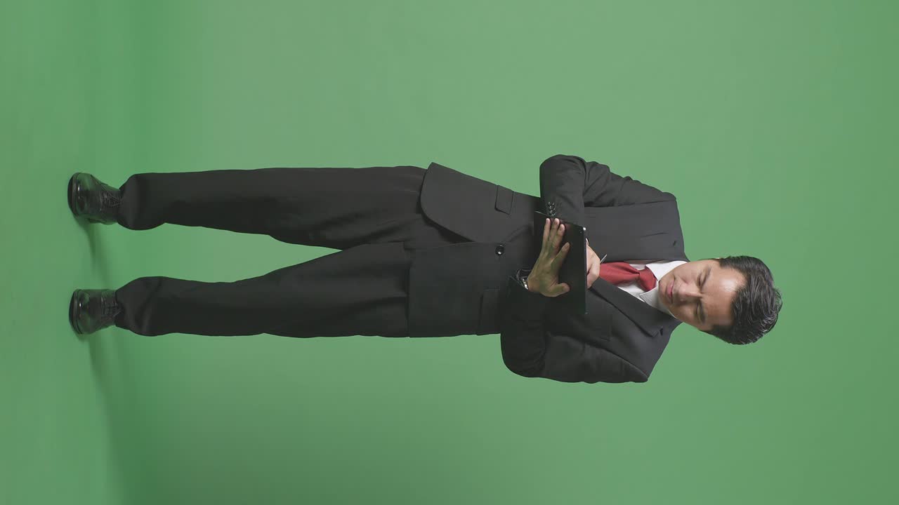 스튜디오에서 녹색 화면 배경에 태블릿을 쓰는 아시아 사업가의 몸이 가득 차 있습니다.