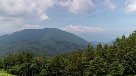 Sich-Schnell-Bewegender-Zeitraffer-Mit-Wolken,-Die-Schatten-Auf-Berge-Werfen,-Mit-Wald-Und-Grün-Im-Vordergrund---Nach-Oben-Geneigter-Schuss