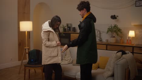 couple getting dressed in warm jackets at home