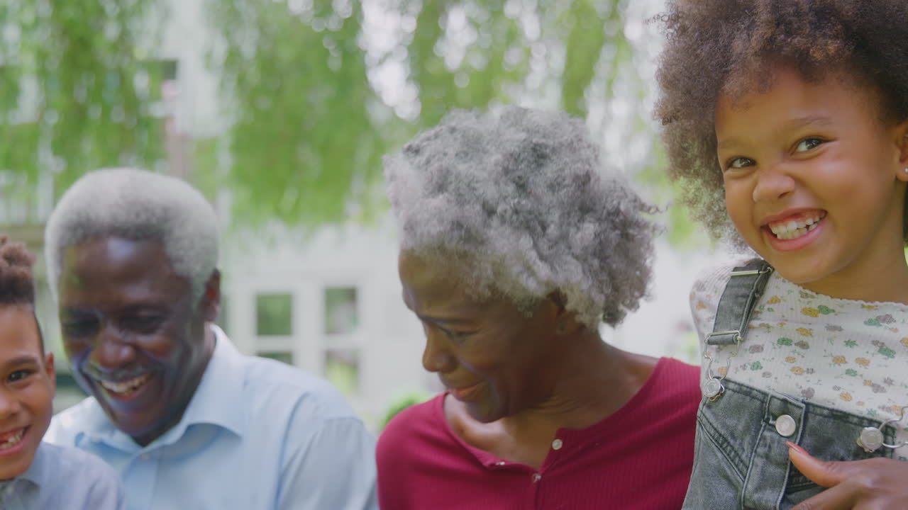 Loving Grandparents Talking With Grandchildren In Garden At Home