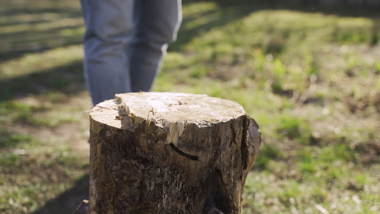 백인 남자가 시골 집 밖에서 도끼로 불 ⁇ 을 자르는 클로즈업 뷰. 그리고 그는 카메라를 본다