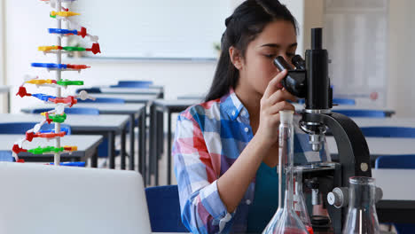 Attentive-schoolgirl-using-laptop-while-experimenting-in-laboratory