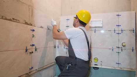 male craftsman installing ceramic tiles on the wall closeup vertical video