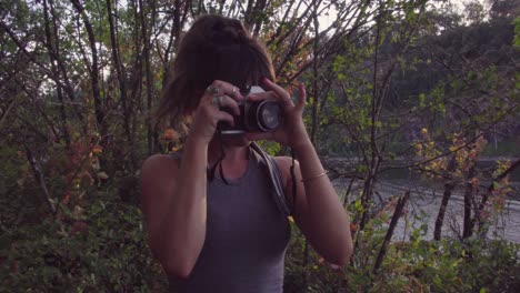 linda chica hipster en un parque enfocando una cámara de cine para tomar una foto