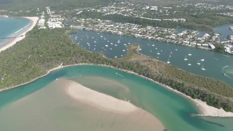 aerial: footage of noosa lagoon with beautiful clear emerald water that flows down from the larger estuary system into the beach