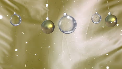 animación de bolas de navidad colgando con nieve cayendo sobre un fondo dorado