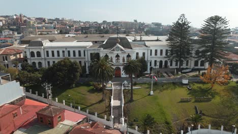 Aerial-lowering-on-National-Maritime-Museum-in-Cerro-Artilleria,-Valparaiso-hillside-city-in-background,-Chile