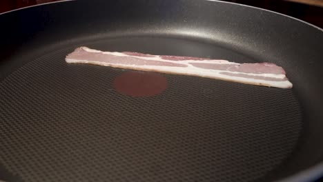 primer plano estático de tocino en rodajas cocinando en una sartén