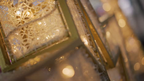 close-up of intricate gold frame with delicate patterns illuminated by warm glowing light, accompanied by soft white and purple light reflections in blurred background