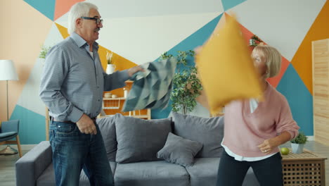 elderly couple having a pillow fight at home