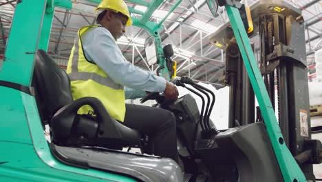 Male-worker-driving-forklift-in-a-warehouse
