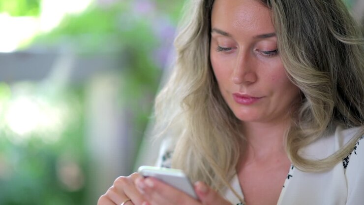 Woman scrolling on her phone at a terrace with a blurry background