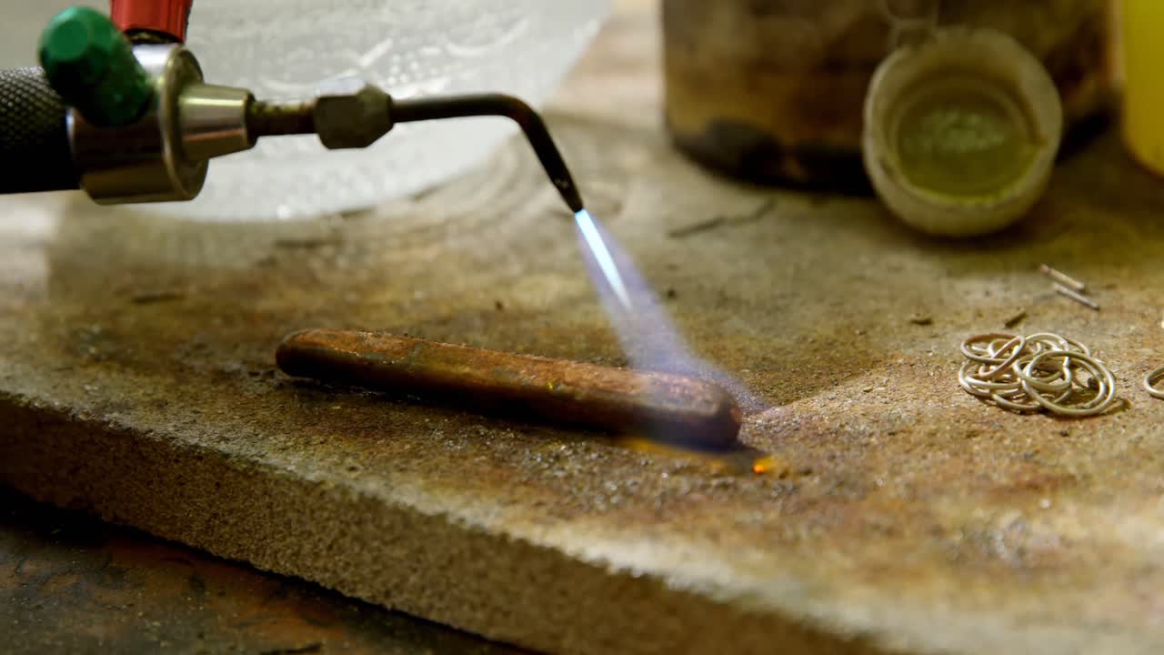 Designer di gioielli che salda un pezzo di metallo in laboratorio 4k