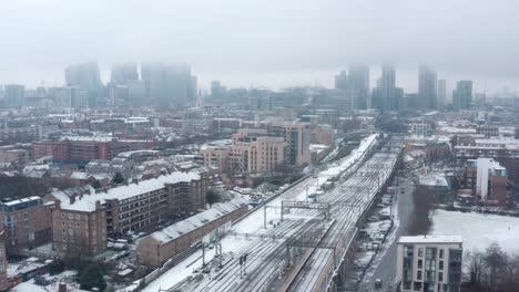 stable aerial drone shot of snow covering central london and train tracks