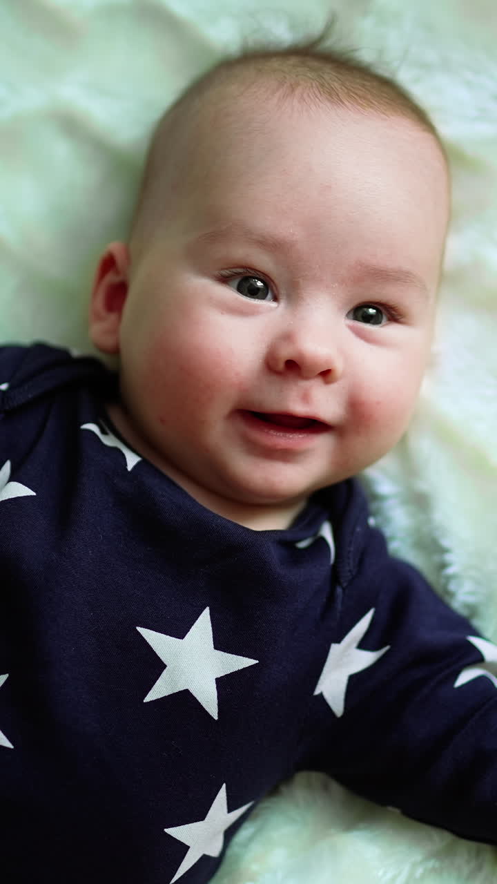Playful baby laying on the bed. Adorable happy little kid smilling. Vertical video