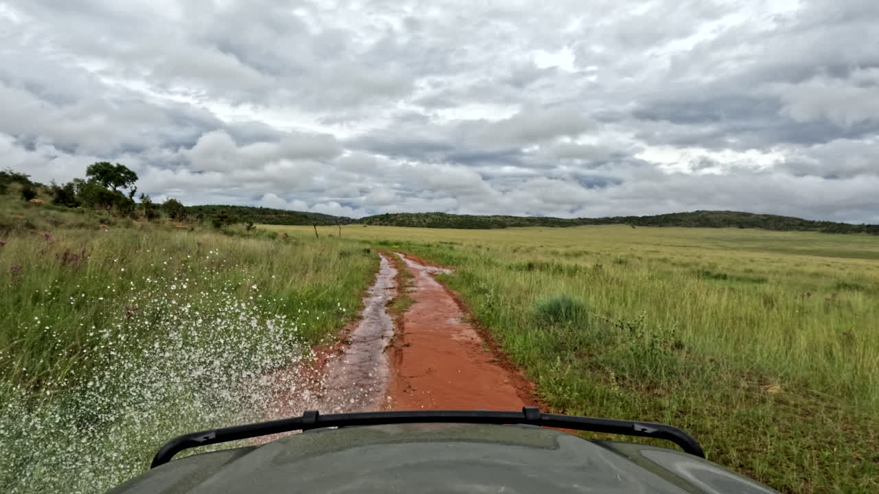 Off-road 4x4 driving on a muddy trail, splashing water under dramatic rain clouds