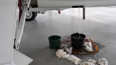 kerosene fuel draining out of hangared aircraft's drain in bucket