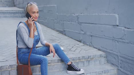 Mixed-race-woman-using-smartphone-sitting-on-outdoor-stairs-