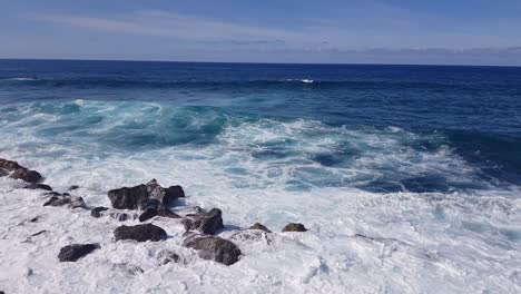 the beautiful blue waves crashing on the rocky shores of the canarian islands, spain - wide shot