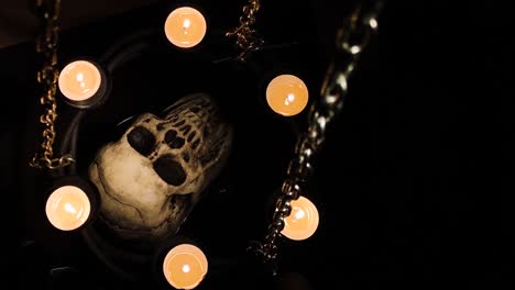 dummy human skull surrounded by candles on chains