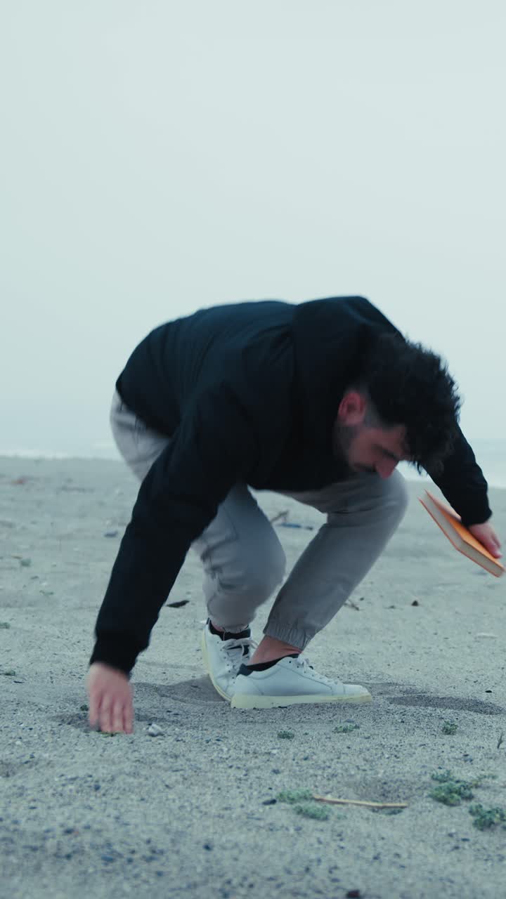Sad Man Starts Reading A Book Sitting On The Sand In Winter
