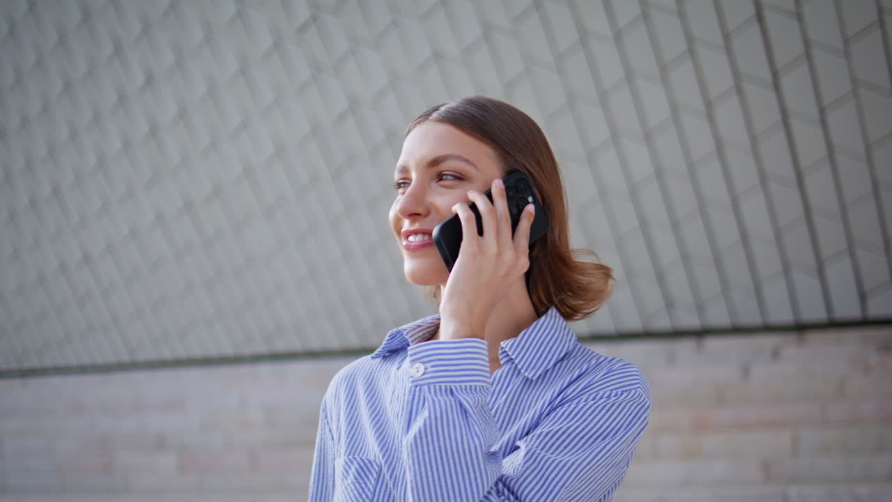 Happy woman talking mobile phone near modern architecture closeup. Smiling lady