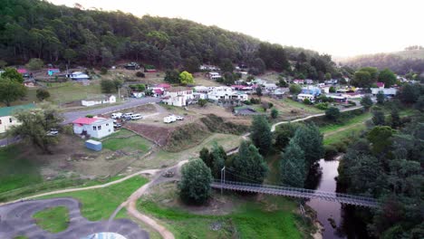 Establishing-aerial-town-with-river-running-by-Derdy,-Tasmania,-Australia