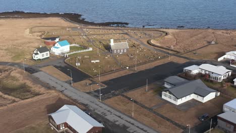 Volando-Hacia-Una-Pequeña-Iglesia-Con-Cementerio-En-La-Costa-Atlántica-De-Islandia,-Antena