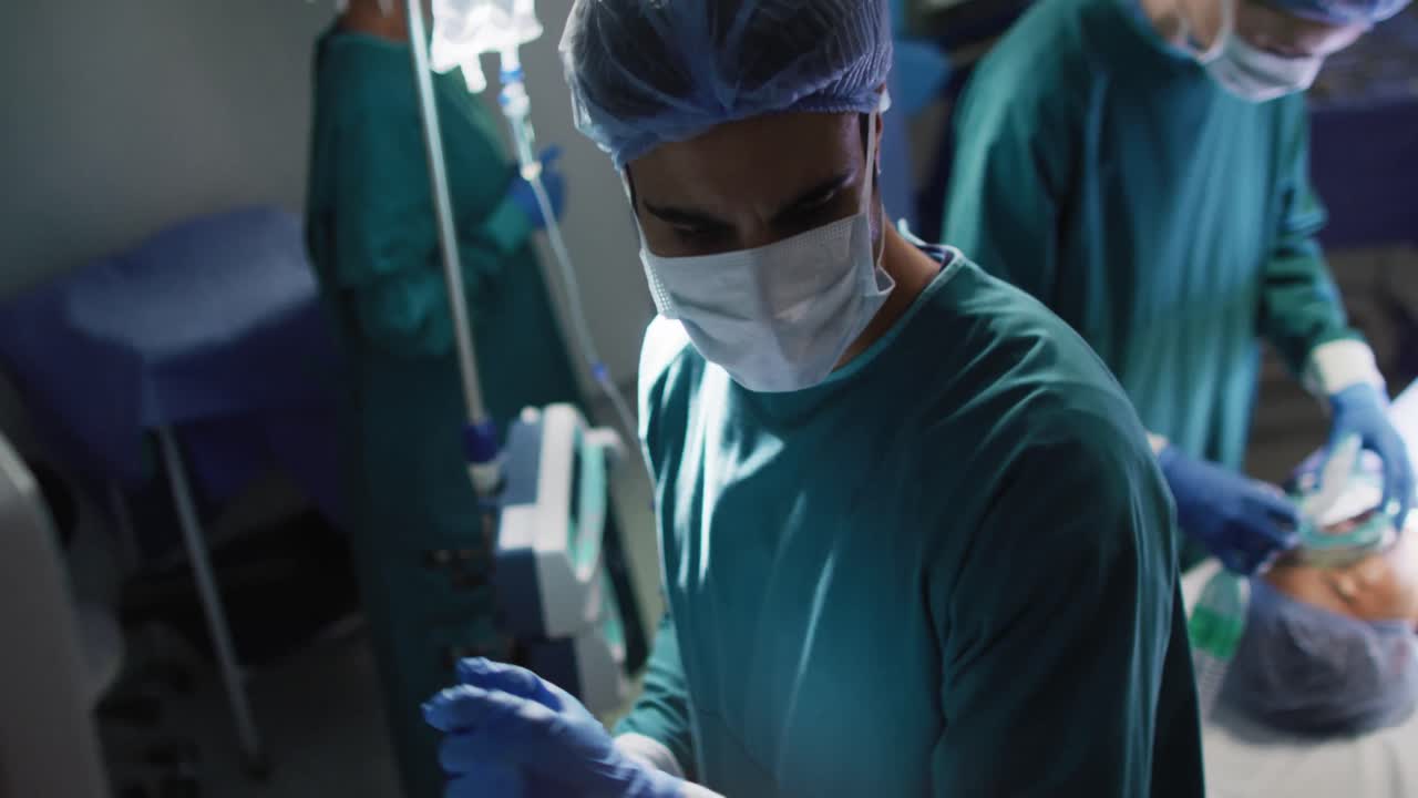 Video of midsection of surgical assistant giving gas to asian female patient in operating theatre